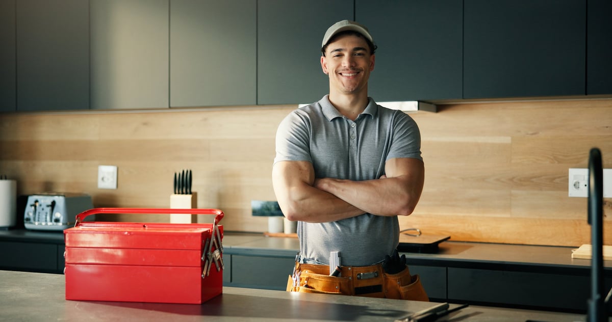 A happy plumber with crossed arms in a kitchen